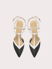 Black and white pointed-toe shoes with studded details on a light gray background