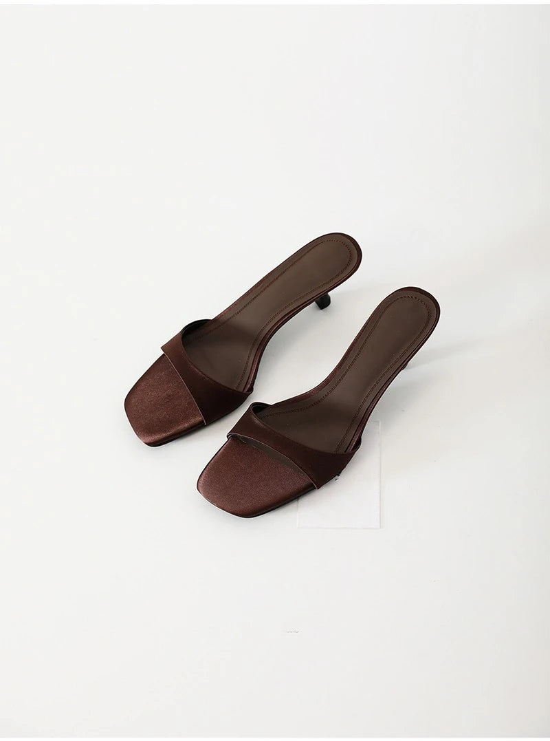 Pair of brown square-toe slippers on a white background