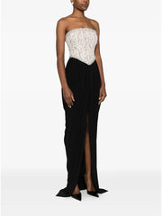 Woman wearing a strapless gown with a white top and black skirt on a white background