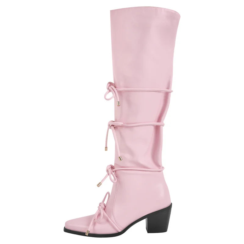 Side view of pink pointed toe knee high boots with bow detail and block heel