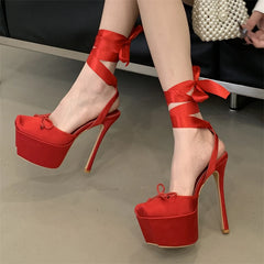 Red high-heeled shoes with ribbon straps on a neutral background