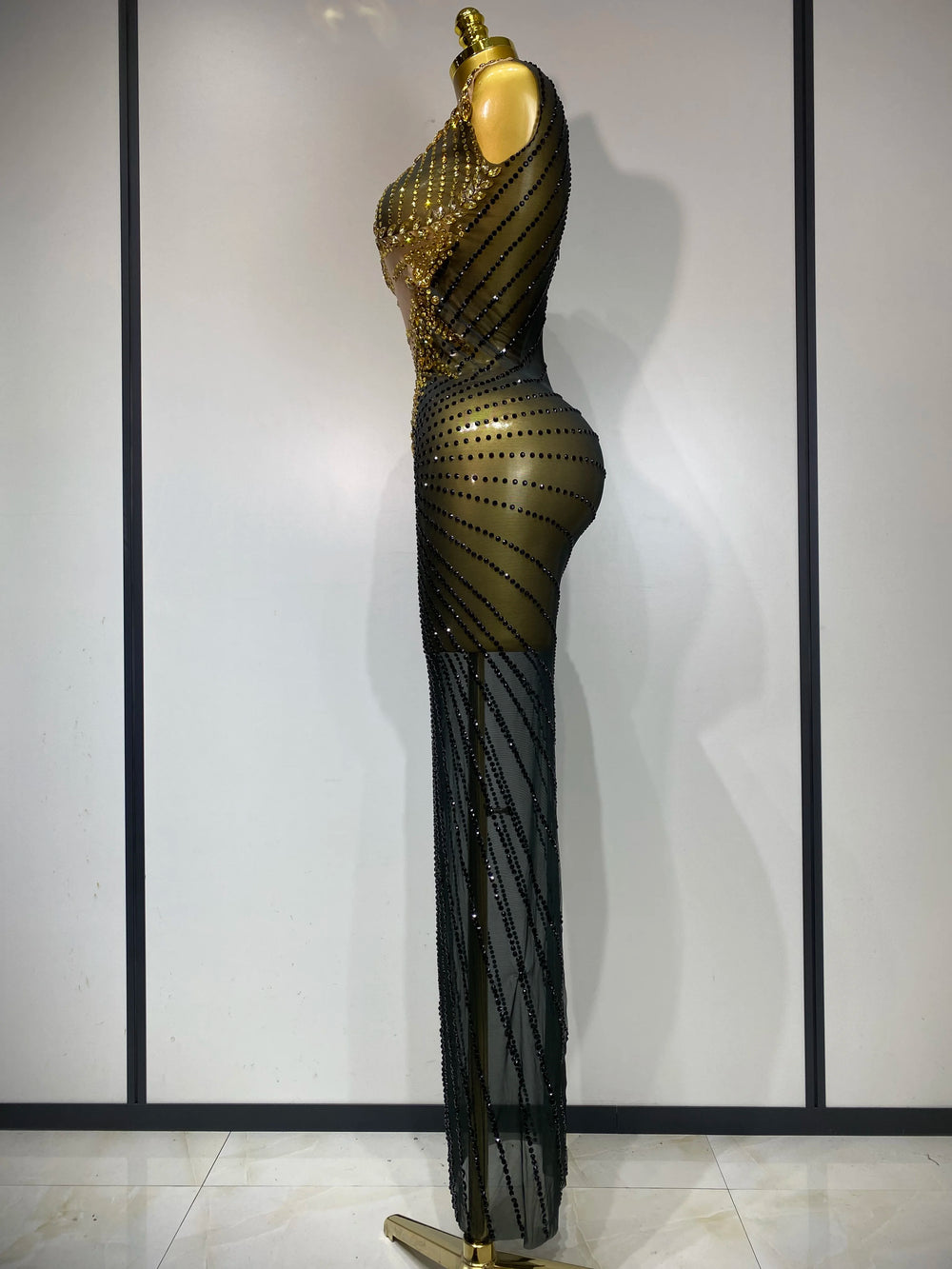 Black and gold evening gown on a mannequin against a white wall.