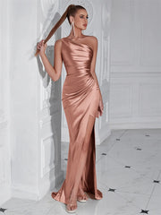 Woman in a rose gold evening gown standing against a white wall.