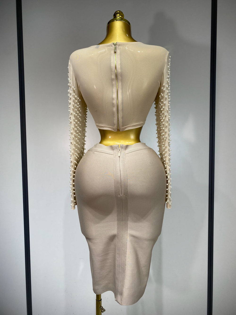 Mannequin wearing a beige dress with sheer sleeves on a gray background