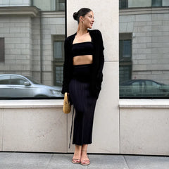 Woman in black outfit standing against a building with reflective surface