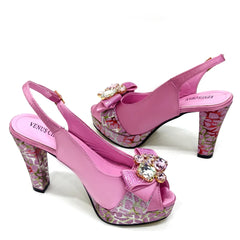 Pink high-heeled shoes with floral patterns and decorative bows on a white background