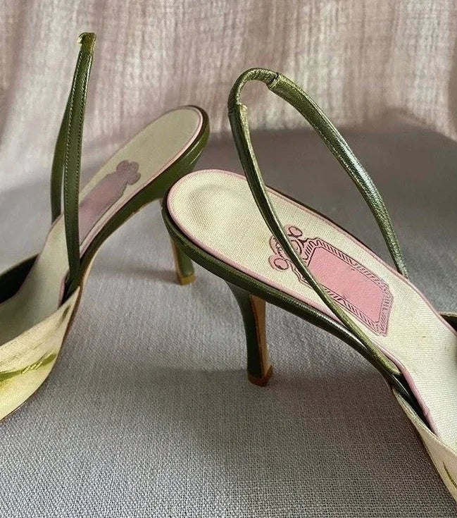 Pair of high-heeled shoes with green straps on a textured surface