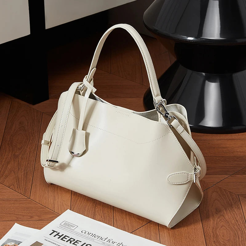 White handbag on a wooden floor with a black lamp in the background