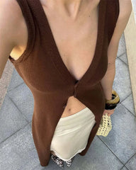 Person wearing a brown sleeveless top with a deep neckline on a tiled floor.