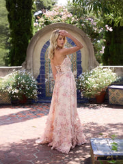Woman in a floral dress standing in a garden with a decorative archway.