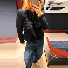 Person wearing a black jacket and blue jeans taking a mirror selfie.
