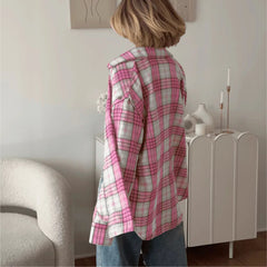 Person wearing a pink and white plaid shirt in a room with a white cabinet and decorative items.