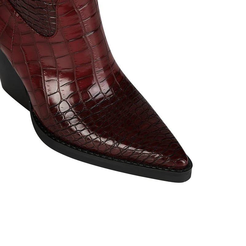Close-up of the pointed toe of a burgundy embellished knee-high western boot.