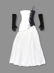 White strapless dress with black accents and gloves on a gray background