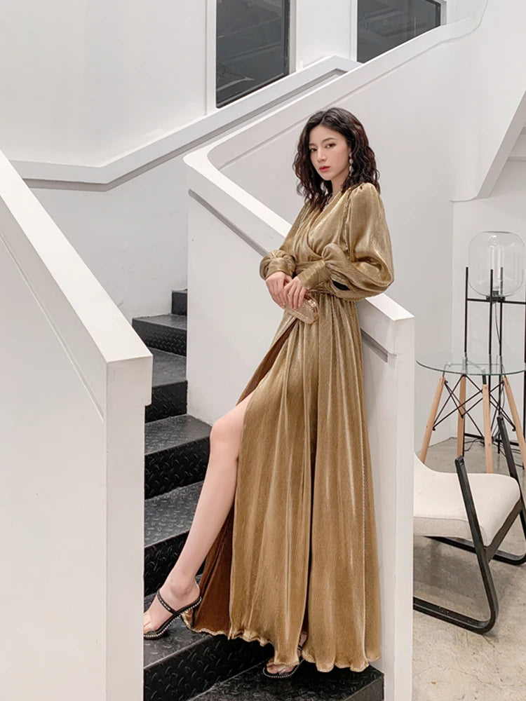 Woman in a gold dress standing on a staircase in a modern interior setting