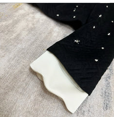 Black leggings with white rhinestone embellishments on a textured surface