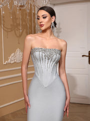 Woman wearing a strapless, embellished evening gown in an elegant indoor setting.