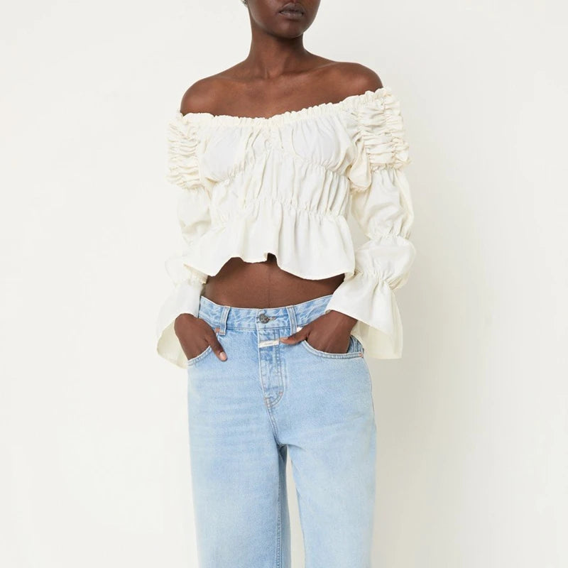 Woman wearing a white off-shoulder top and light blue jeans on a white background