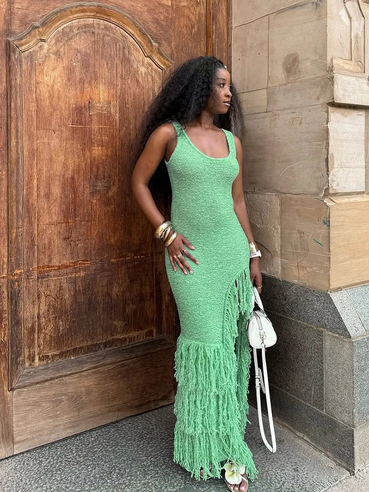 Woman wearing a green knit midi dress with tassel hem and slit