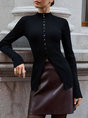 Person wearing a black ribbed sweater and brown leather skirt standing against a stone wall.