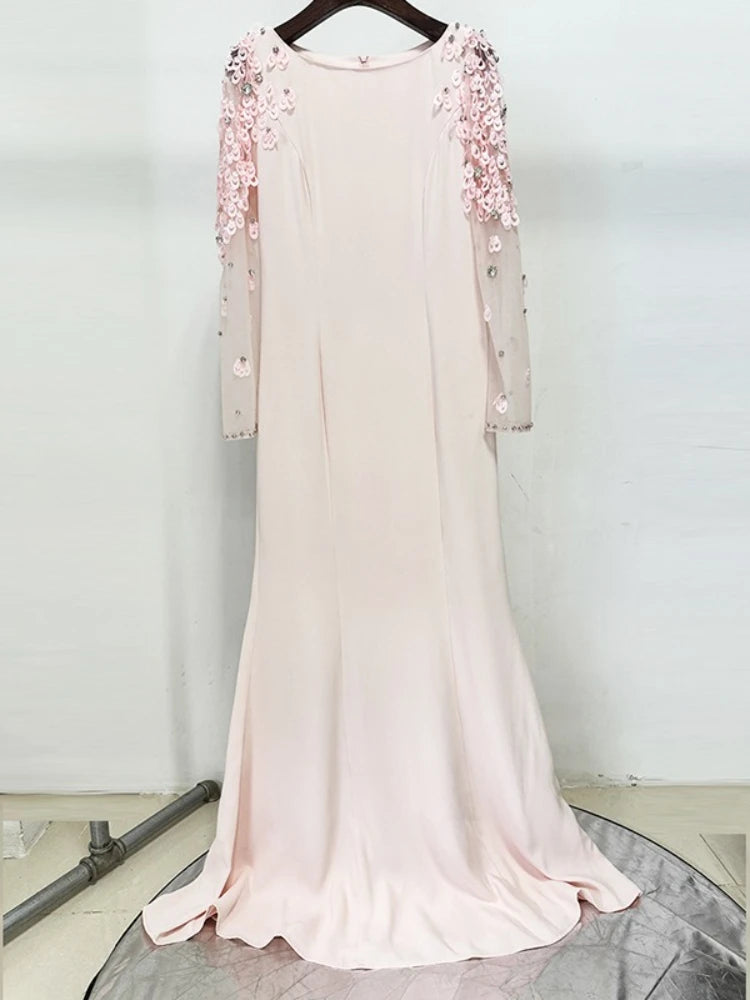 Pink evening gown with floral embellishments on a hanger against a white background