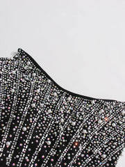 Black dress with bead detailing on a light gray background