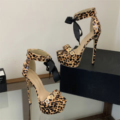 Leopard print platform stiletto lace-up sandals styled against a dark box.