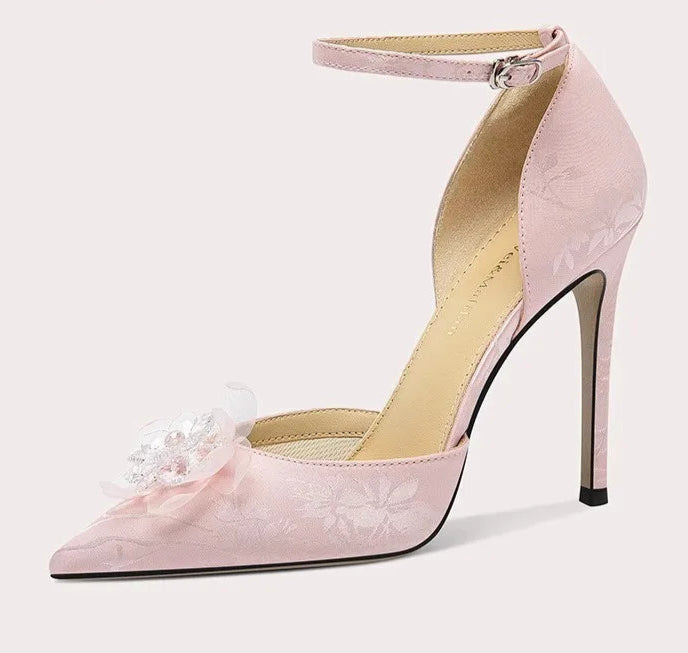 Pink high-heeled shoe with floral detail on a white background