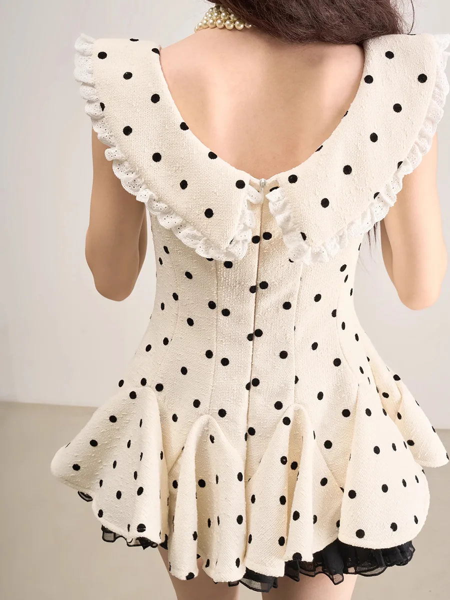 White dress with black polka dots and ruffled sleeves on a plain background