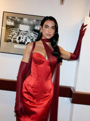 Woman in a red dress with long gloves posing indoors.
