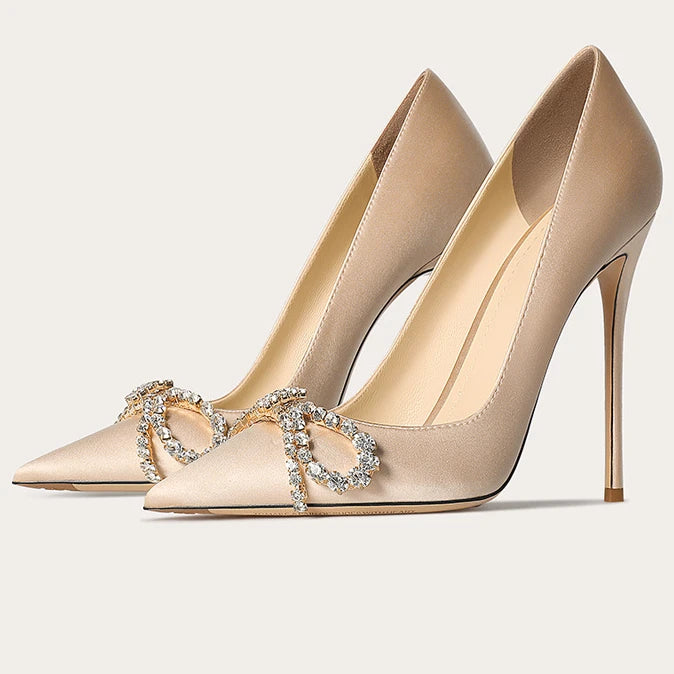 Beige high-heeled shoes with a decorative heart brooch on a light background
