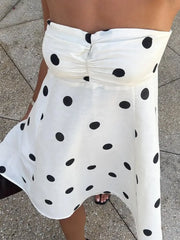 White polka dot skirt on a person standing on a pavement.