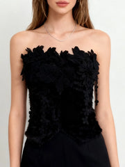 Black strapless top with floral details on a plain background