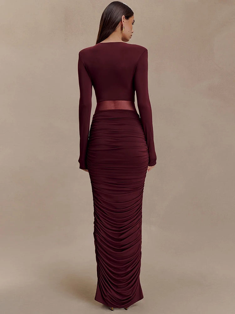 Maroon two-piece outfit with long sleeves and ruched skirt on a beige background