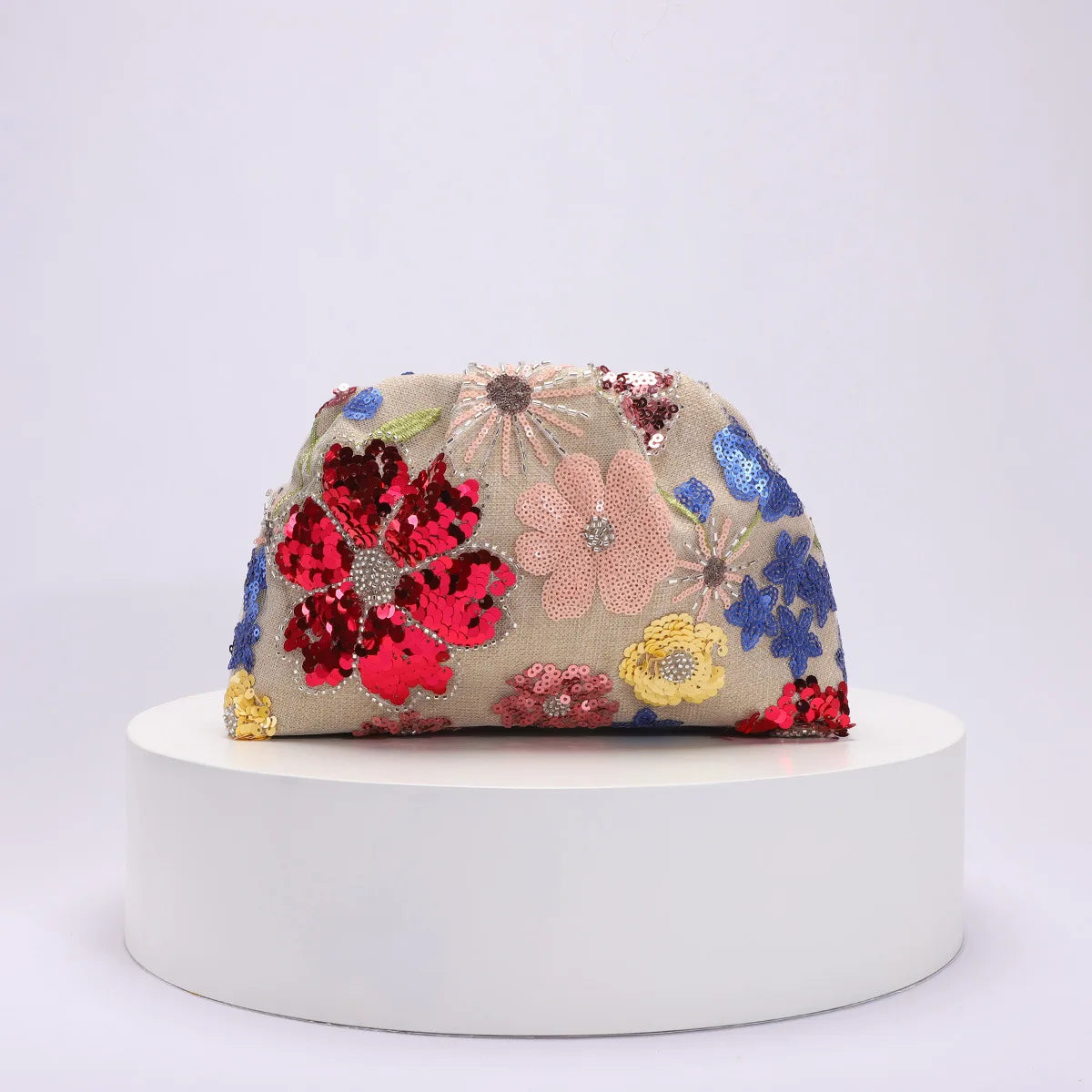 Colorful floral embroidered clutch bag on a white platform with a light gray background