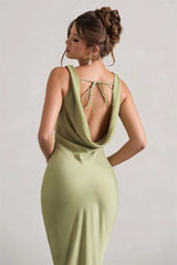 Woman wearing a light green dress with a open back on a plain background