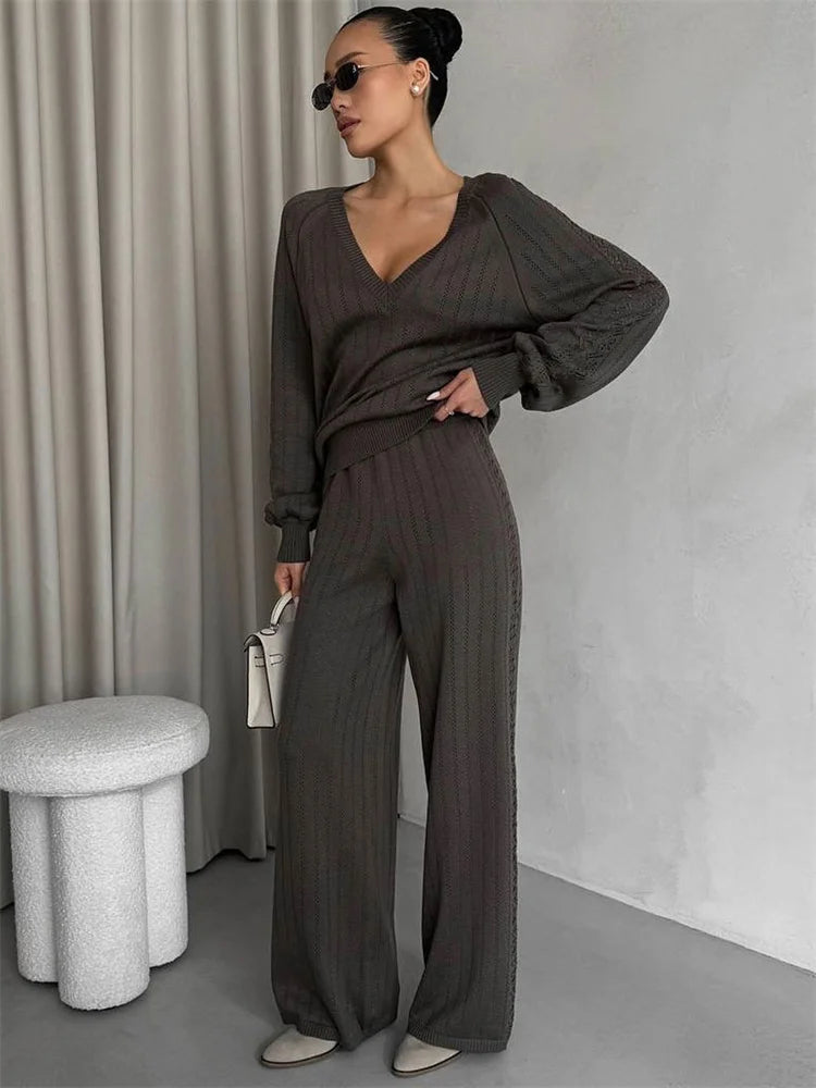Woman wearing a brown outfit with wide-leg pants in a minimalistic setting.