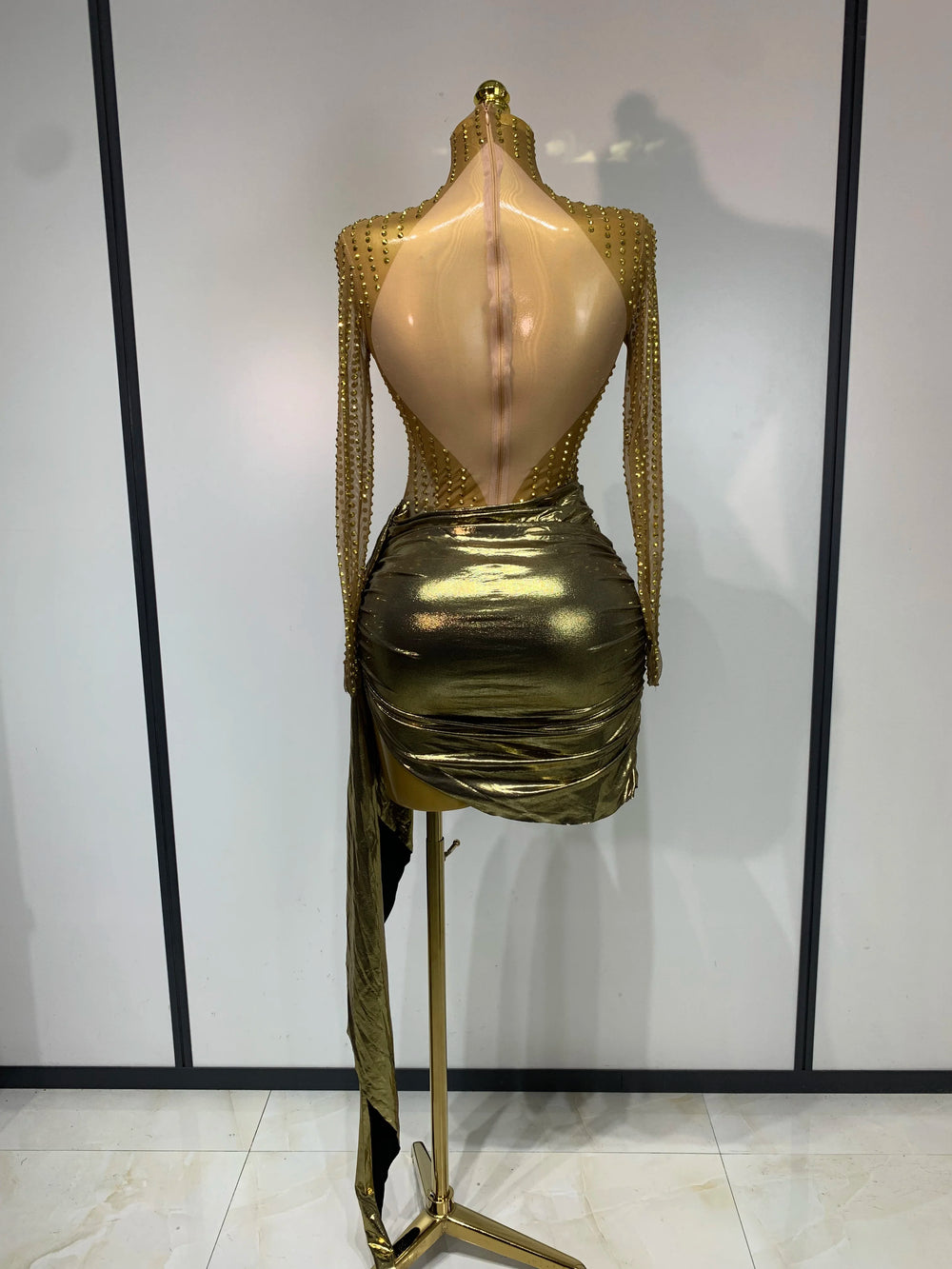 Back view of gold long sleeve turtleneck mini dress with embellishments and draped skirt