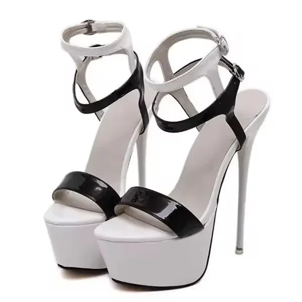 White high-heeled platform shoes with black patent leather straps on a white background