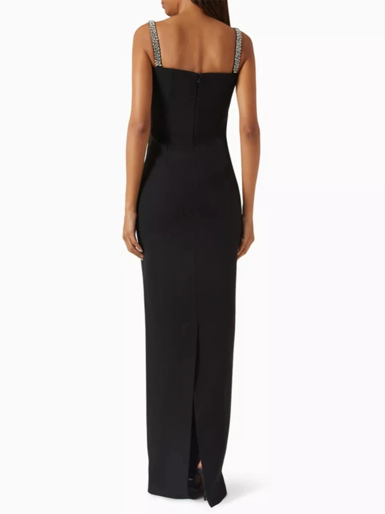 Black evening gown with thin straps and a slit on a white background