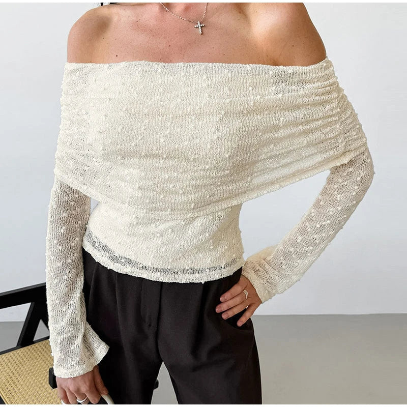 Person wearing a white off-shoulder top with long sleeves against a plain background