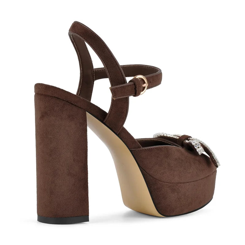 Close-up side view of brown faux suede platform sandals with rhinestone bow