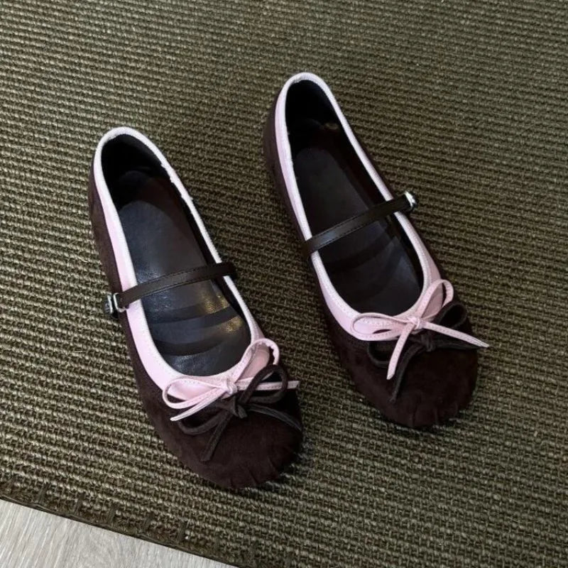Pair of brown shoes with pink bows on a textured surface