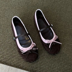 Pair of brown shoes with pink bows on a textured surface