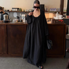 Woman in a solid black maxi dress with a loose fit