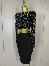 Black pearl embelished top and skirt set with long sleeves on a mannequin against a white background.