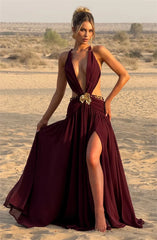 Woman in a burgundy evening gown with a high slit standing in a desert landscape.