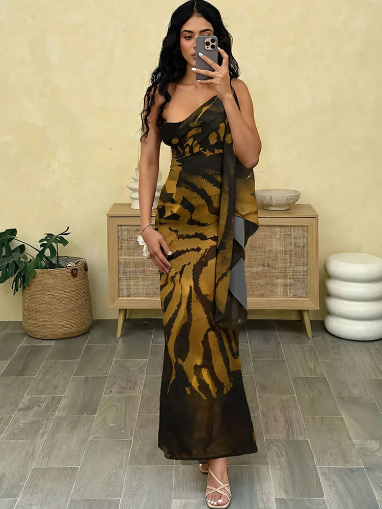 Woman taking a mirror selfie wearing a black and yellow patterned dress in a room with a beige wall and wooden cabinet.