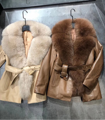 Two leather jackets with fur collars hanging on a gray surface.