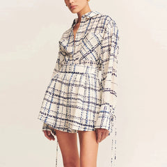 Woman wearing a plaid dress with long sleeves on a plain background